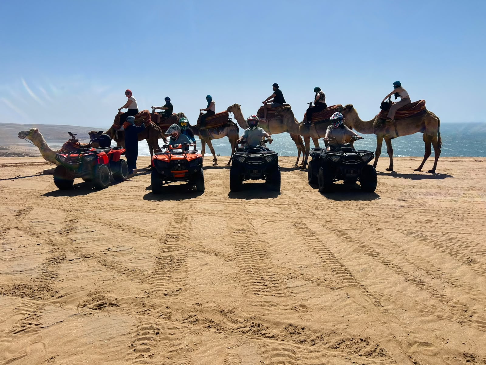 Quad ATV riders and camel riders together on the beach at Timlalin — a unique combo experience